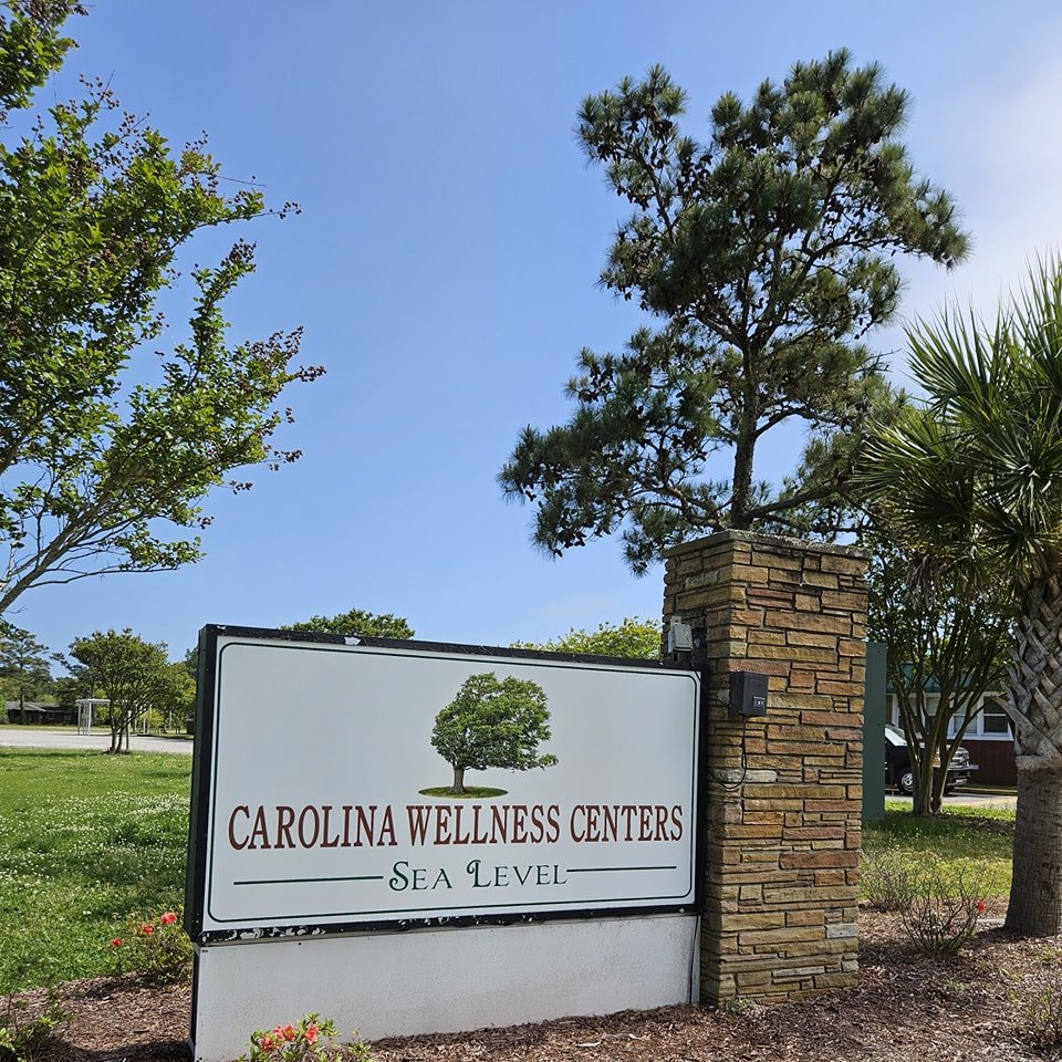 Carolina Wellness Centers at Sea Level entrance sign beside coastal trees